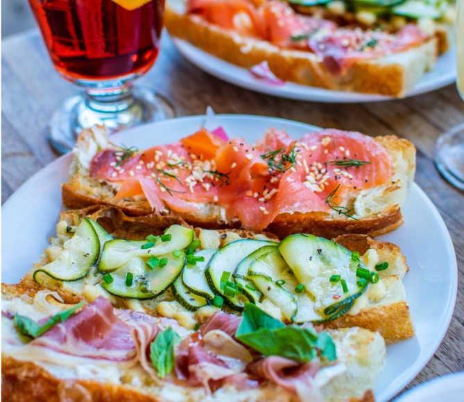 Three pieces of bread, one with salmon on top, one with zucchini, and one with proscuitto.