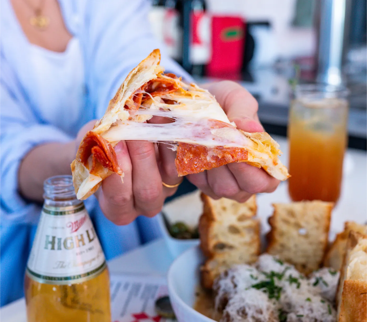 A woman tears a piadina with pepperoni inside of it in half.