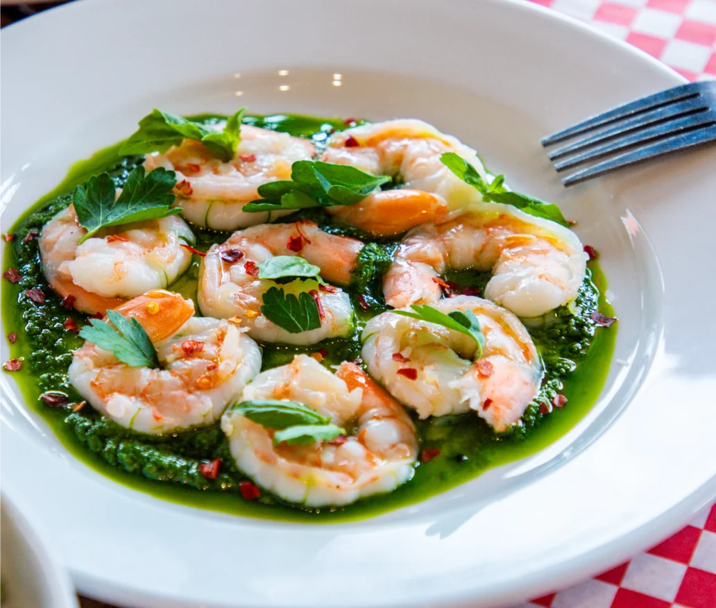 A plate of chilled poached shrimp over basil pesto.