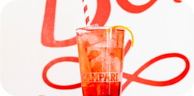Close-up of a negroni cocktail inside of a glass reading "Campari".